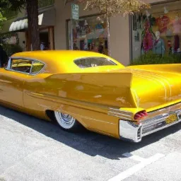 Żółty, odrestaurowany samochód typu lowrider z białymi oponami, zaparkowany na ulicy w Bielsko-Białej, z widocznymi detalami chromowanymi i białymi zdobieniami.