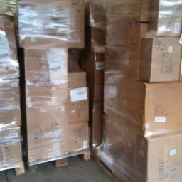 Kartonowe pudła zabezpieczone folią stretch na drewnianych paletach, załadowane w przestrzeni ładunkowej pojazdu dostawczego.