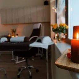 Przytulne wnętrze salonu w Świeciu, z zapaloną świecą na pierwszym planie, w tle fotel kosmetyczny i stolik zabiegowy.