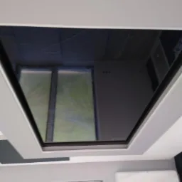 Nowoczesny sufit z wbudowanym oknem dachowym, widok z dołu, szare ściany, klimatyzator.