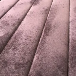 Detale pionowych przeszyć na panelu ściennym z miękkiej, fioletowo-różowej tkaniny o delikatnej fakturze. Widoczne subtelne cieniowania i załamania światła podkreślające głębię koloru.