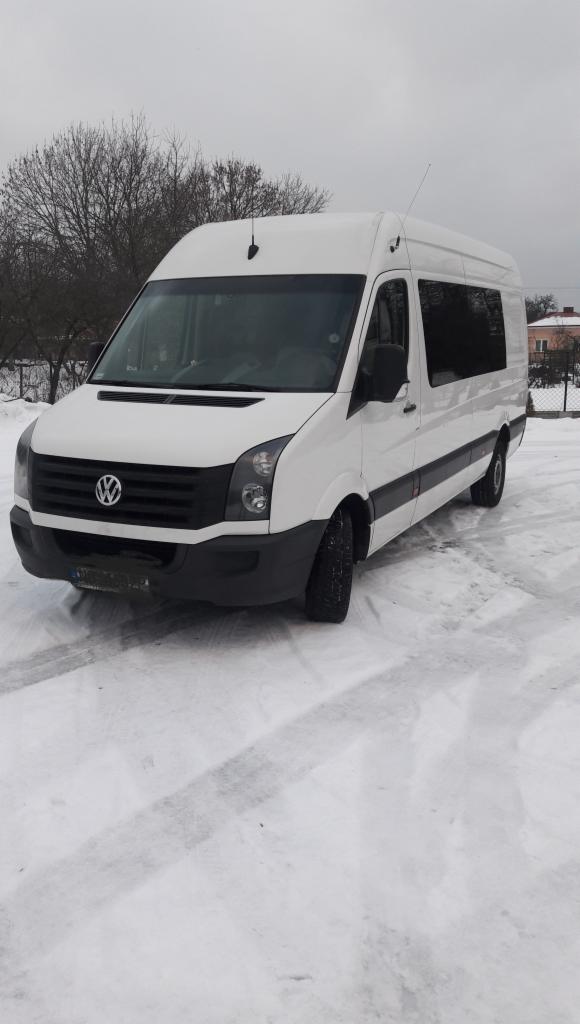 Biały bus Volkswagen Crafter na ośnieżonym terenie w pochmurny dzień, widoczny z przodu pod lekkim kątem.