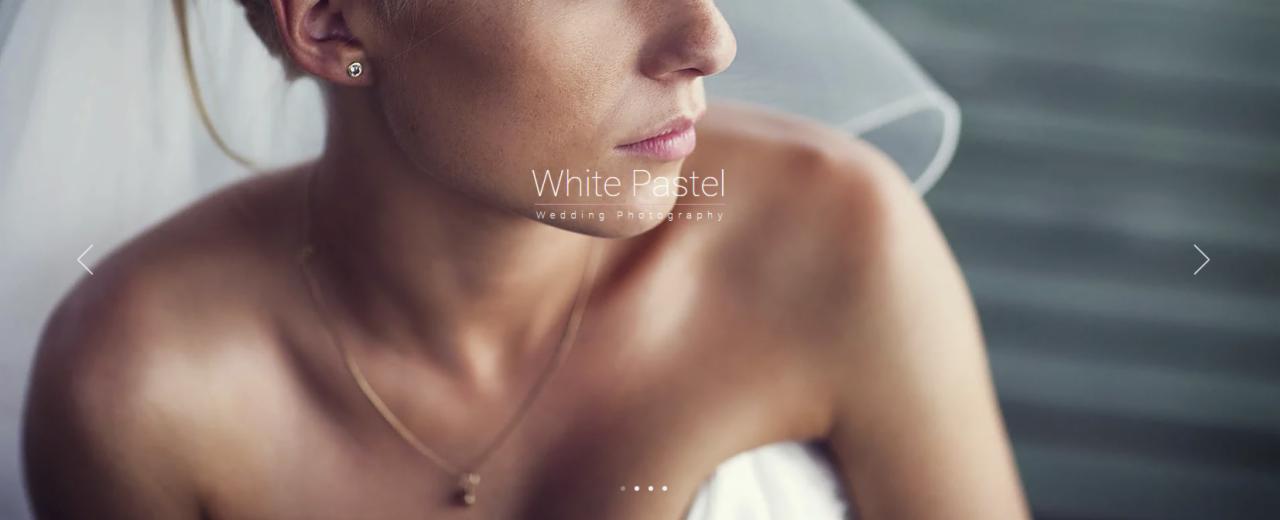 Portret panny młodej w delikatnym makijażu, z widoczną biżuterią: złotym łańcuszkiem i kolczykiem. Ujęcie z bliska, z welonem w tle.