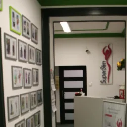 Wnętrze kliniki z galerią zdjęć metamorfoz pacjentów na ścianie, recepcją i logo 'SuperSlim' na ścianie w tle.