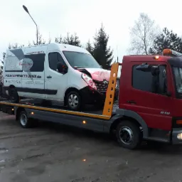 Uszkodzony biały bus z logo firmy przewozowej Wama-bus załadowany na lawetę pomocy drogowej