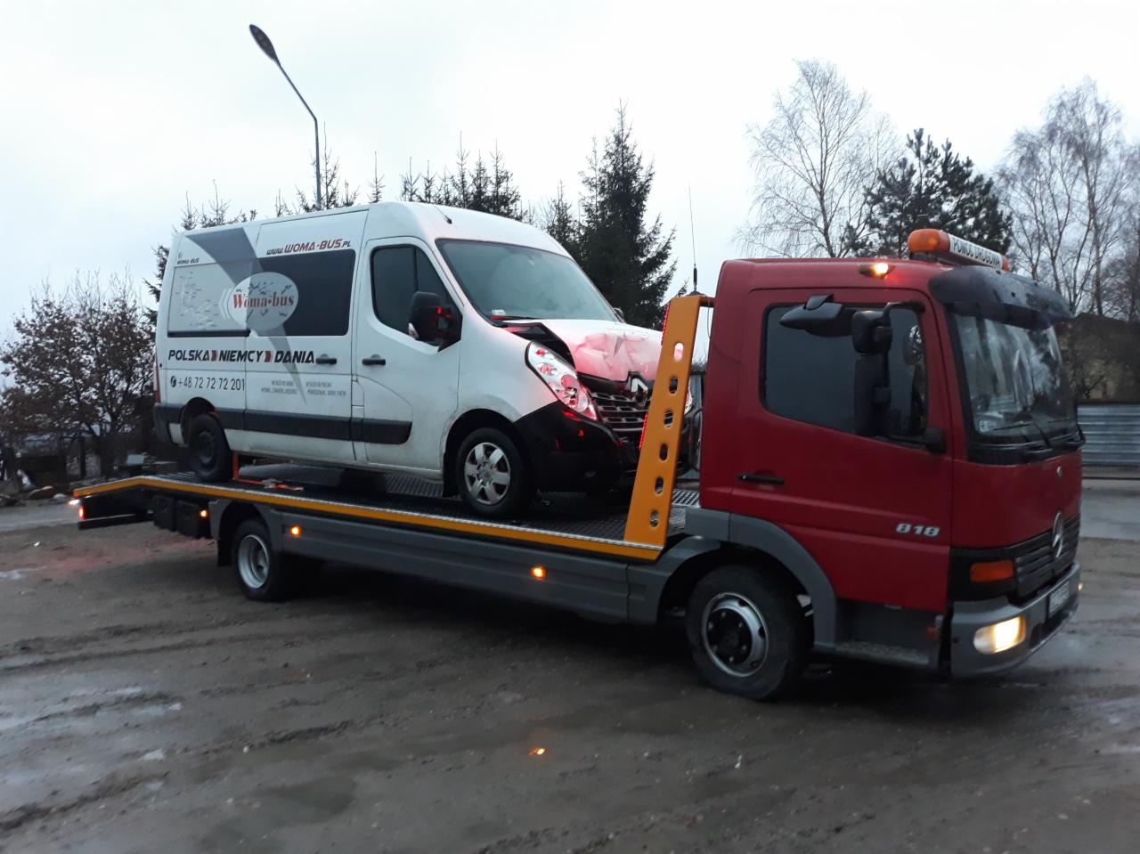 Uszkodzony biały bus z logo firmy przewozowej Wama-bus załadowany na lawetę pomocy drogowej