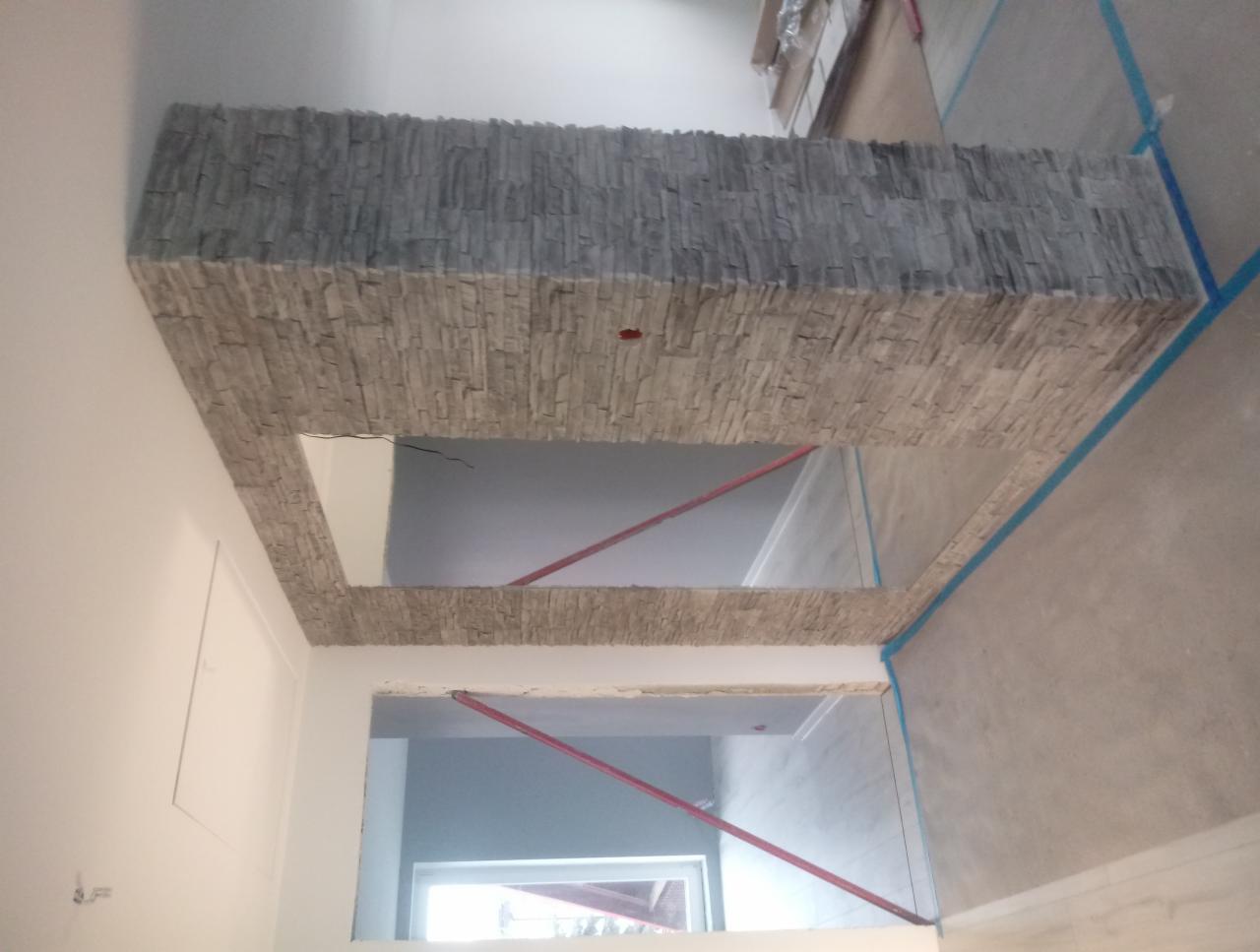 Wykończenie sufitu i ściany płytami imitującymi kamień naturalny, widoczne profile i taśmy malarskie zabezpieczające, wnętrze w trakcie remontu.