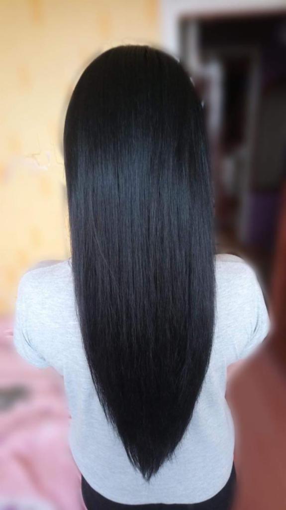 Długie, proste, czarne włosy z tyłu głowy, układające się w kształt litery V, na tle rozmytej ściany i różowego koca.