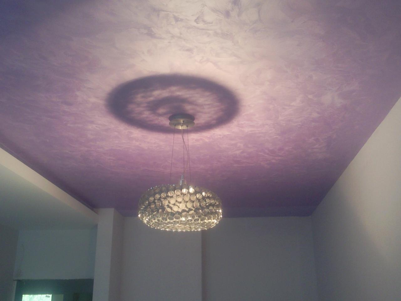 Fioletowy sufit z dekoracyjną fakturą i wiszącą lampą, rzucającą okrągły cień.