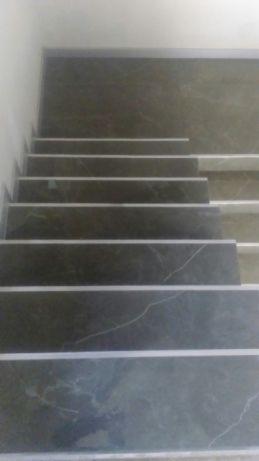 Schody wyłożone ciemnym gresem z białymi żyłkami i aluminiowymi listwami krawędziowymi, widok z góry.