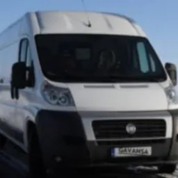 Biały bus Fiat Ducato zaparkowany na ośnieżonej drodze w zimowy dzień, widoczna tablica rejestracyjna z napisem 'GAVANSA'.