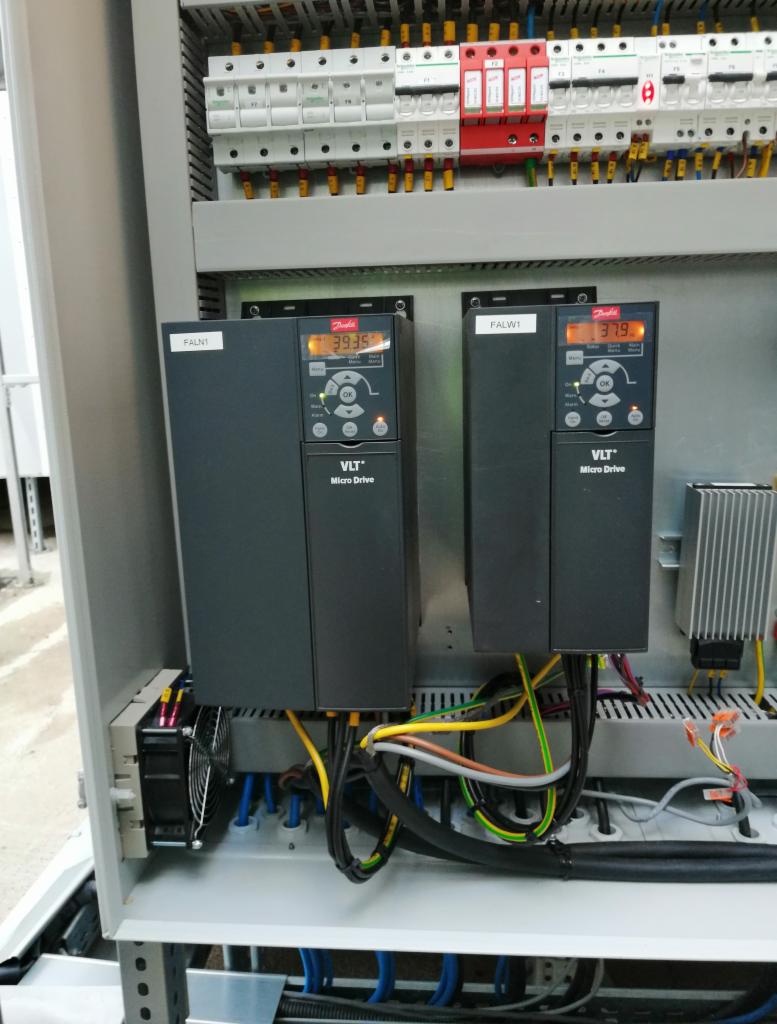 Dwa falowniki Danfoss VLT Micro Drive zamontowane w szafie sterowniczej, widoczne okablowanie i zabezpieczenia nadprądowe.
