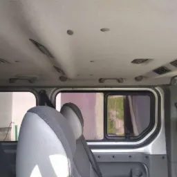 Wnętrze busa z widocznymi fotelami pasażerów, oknami i elementami oświetlenia podsufitowego.