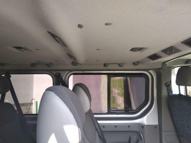 Wnętrze busa z widocznymi fotelami pasażerów, oknami i elementami oświetlenia podsufitowego.