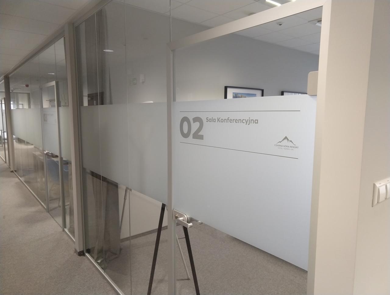 Oznakowanie szklanej ściany sali konferencyjnej numer 02 z nazwą i logo Czarna Góra Resort, widok z korytarza.