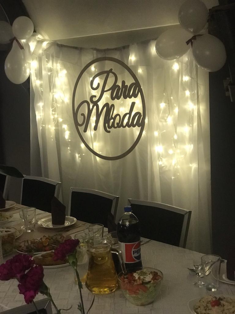 Uroczysta dekoracja sali weselnej: drewniany napis 'Para Młoda' otoczony lampkami, białe balony, zastawiony stół z daniami, napojami i kwiatami.