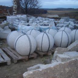 Kopalnia Granitu Górbeh - Magazyn kostki granitowej: Granitowe kule na paletach, kostka w workach i bloczki w tle, pochmurne niebo.