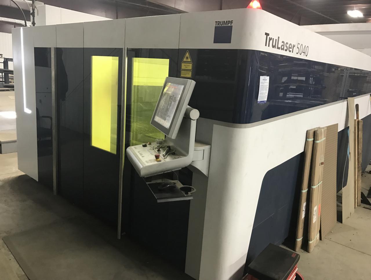 Duża maszyna TRUMPF TruLaser 5040 z panelem sterowania i żółtymi szybami ochronnymi w hali produkcyjnej.