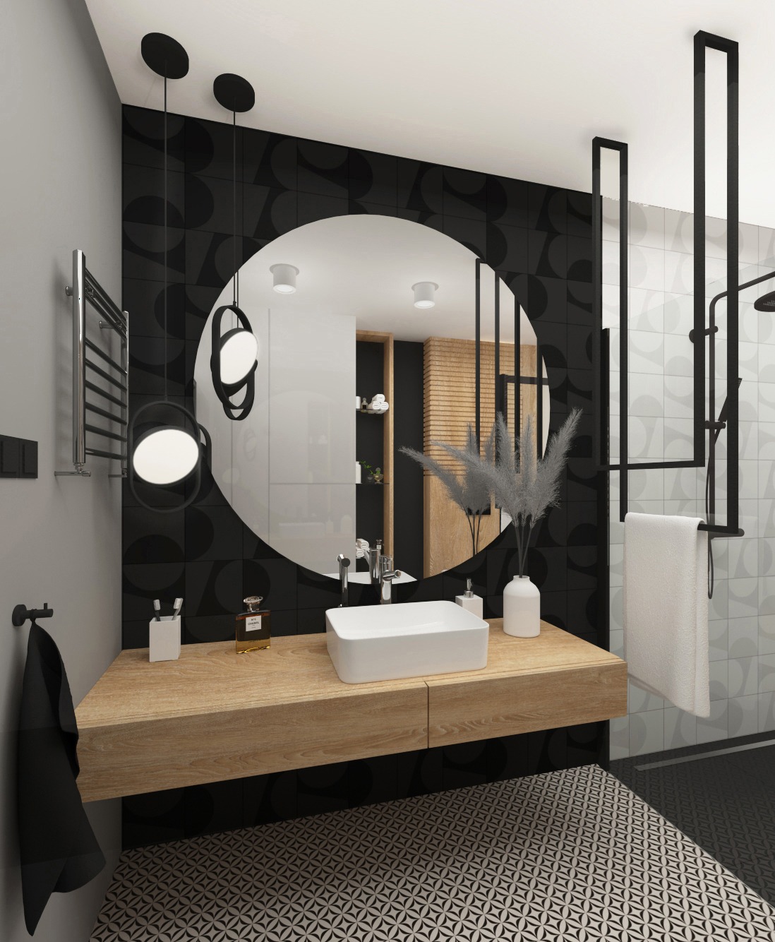 Nowoczesna łazienka z okrągłym lustrem, drewnianym blatem pod umywalką i czarno-białymi płytkami podłogowymi w geometryczny wzór. Widoczny grzejnik drabinkowy, wisząca lampa i czarny ręcznik.