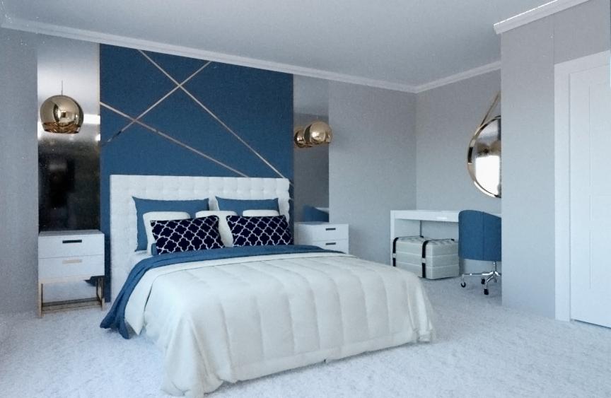Nowoczesna sypialnia z niebieską ścianą zdobioną złotymi liniami, białe łóżko z niebieskimi akcentami, złote lampy wiszące i lustro w kształcie koła nad biurkiem.
