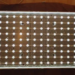 Otwarty panel LCD telewizora z podświetleniem LED, widoczne listwy LED z diodami, tło rozmyte.