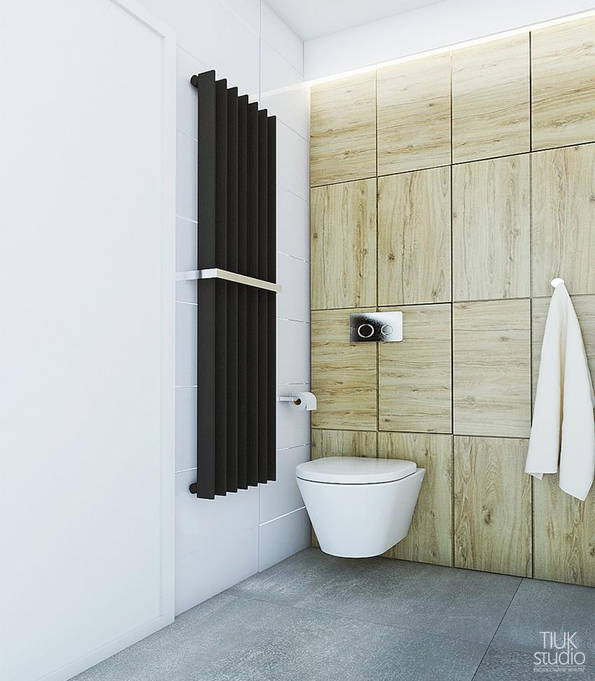 Nowoczesna toaleta podwieszana z czarnym grzejnikiem drabinkowym i ścianą wyłożoną drewnopodobnymi płytkami w kwadraty.