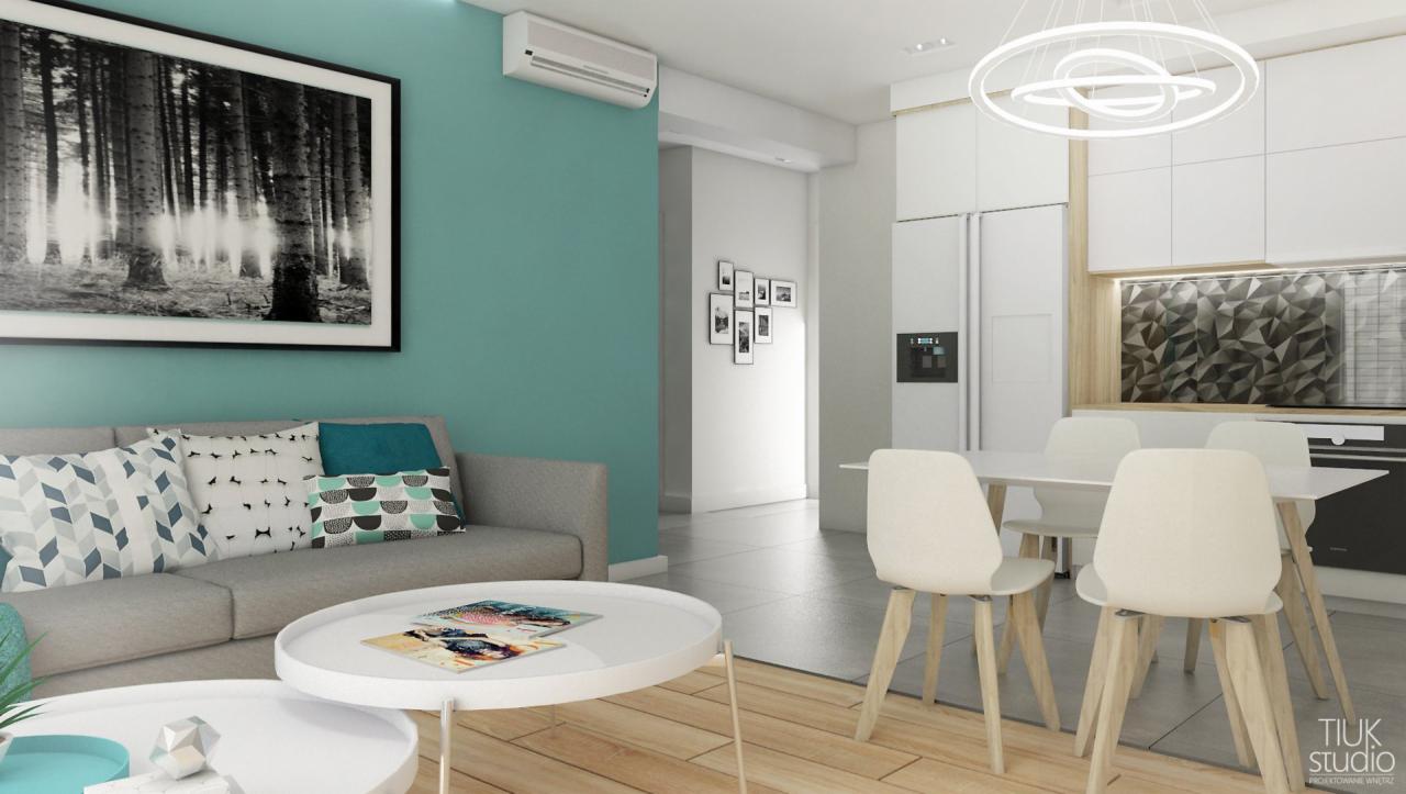 Jasne, przestronne wnętrze mieszkania z turkusową ścianą, szarą sofą z wzorzystymi poduszkami, okrągłymi stolikami kawowymi i nowoczesnym oświetleniem nad stołem jadalnym z krzesłami w stylu...