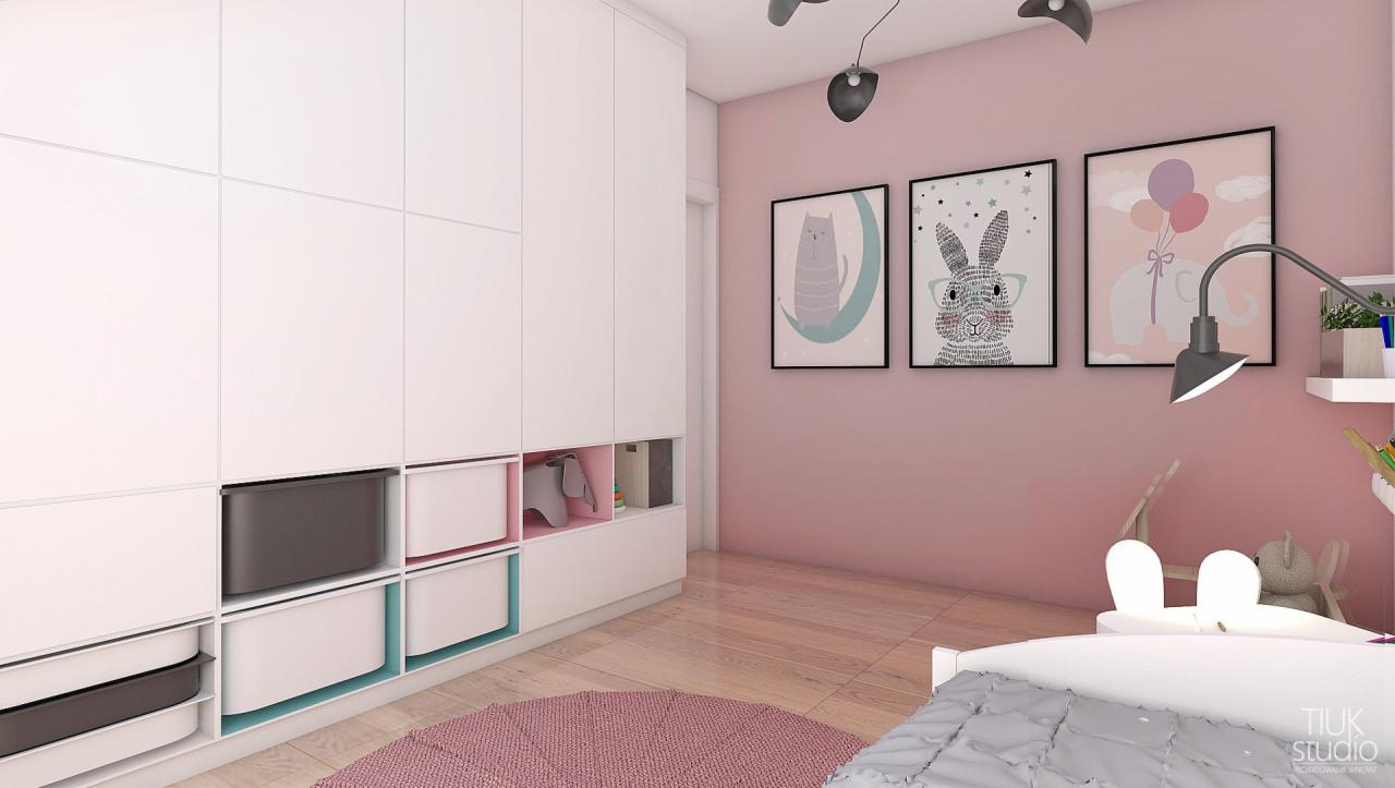 Pokój dziecięcy w pastelowych kolorach z białymi meblami modułowymi, okrągłym różowym dywanem i trzema obrazkami ze zwierzętami na ścianie.