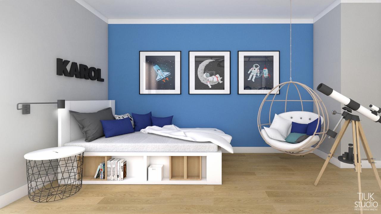 Pokój dziecięcy w tematyce kosmicznej: łóżko z regałem, wiszące krzesło-kokon, teleskop i grafiki z astronautami na niebieskiej ścianie.