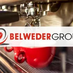 Profesjonalny ekspres do kawy z logotypem Belweder Group i czerwoną filiżanką, zbliżenie na grupę zaparzającą i metalową tackę ociekową.