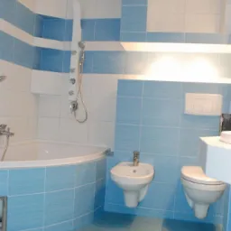 Jasna łazienka z niebiesko-białymi płytkami, armaturą i kabiną prysznicową, widoczny bidet i toaleta. Na dolnej krawędzi zdjęcia widoczne dane kontaktowe firmy.