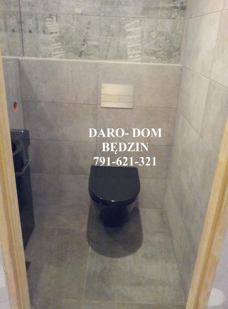 Szara łazienka z czarną toaletą podwieszaną i płytkami imitującymi gazety na górnej części ściany.