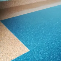 Błękitna i beżowa podłoga z drobnym wzorem, widoczne połączenie kolorów w rogu pomieszczenia.