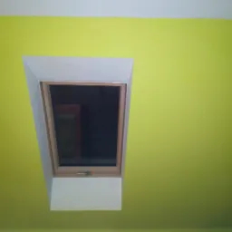 Pomalowane na jaskrawożółty kolor poddasze z oknem dachowym w białej ramie, widoczne z dołu.