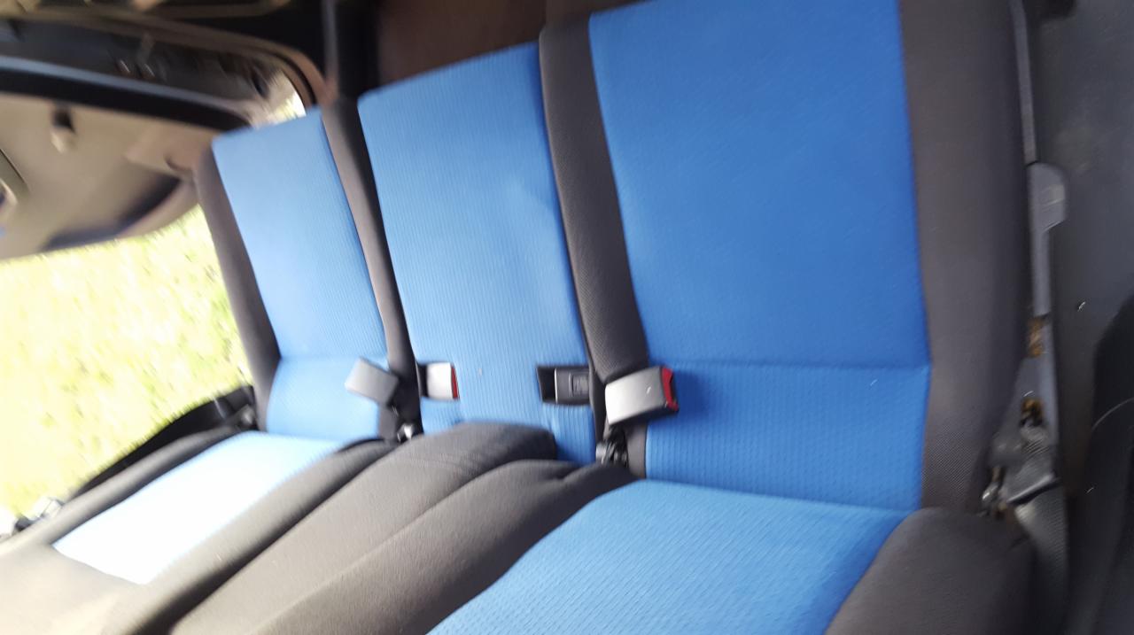 Niebieska tapicerka siedzeń samochodowych z czarnymi pasami bezpieczeństwa i zagłówkami, widok z wnętrza pojazdu.