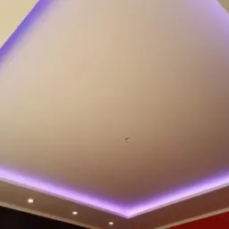 Nowoczesny sufit podwieszany z fioletowym oświetleniem LED, widoczne punkty świetlne wzdłuż ściany.