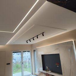 AIRLESS - Nowoczesny salon w Szczecinie po remoncie, z podwieszanym sufitem z oświetleniem LED, marmurową ścianą TV i szynoprzewodem z reflektorami.