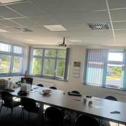 AIRLESS - Jasne biuro z dużym stołem konferencyjnym, roletami w oknach i widocznymi śladami porządkowania po sprzątaniu, w tle torba z logo sklepu.