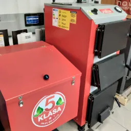 Nowoczesny, czerwono-szary piec CO klasy 5 z podajnikiem, widoczny certyfikat i panel sterowania, na tle systemów sterowania ogrzewaniem.