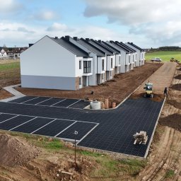 DAS-BUD - Widok z góry na nowo wybudowane szeregówki z wykonanym parkingiem z ażurowych płyt, teren przygotowywany pod drogę dojazdową z użyciem mini koparki.