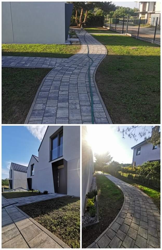 Kręta ścieżka z szarej kostki brukowej prowadząca przez trawnik obok nowoczesnego domu, z widocznym zielonym wężem ogrodowym na kostce.