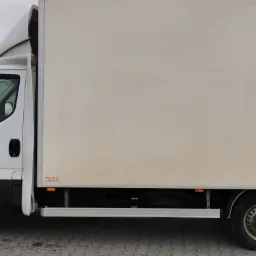 Biały samochód dostawczy z nadbudową kabiny, widok z boku na zaparkowany pojazd z widocznym logo Tensa Automotive na boku skrzyni ładunkowej.