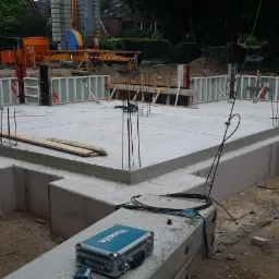 Wylany fundament pod budynek z widocznymi szalunkami, wystającymi prętami zbrojeniowymi i skrzynką narzędziową Makita w pierwszym planie.