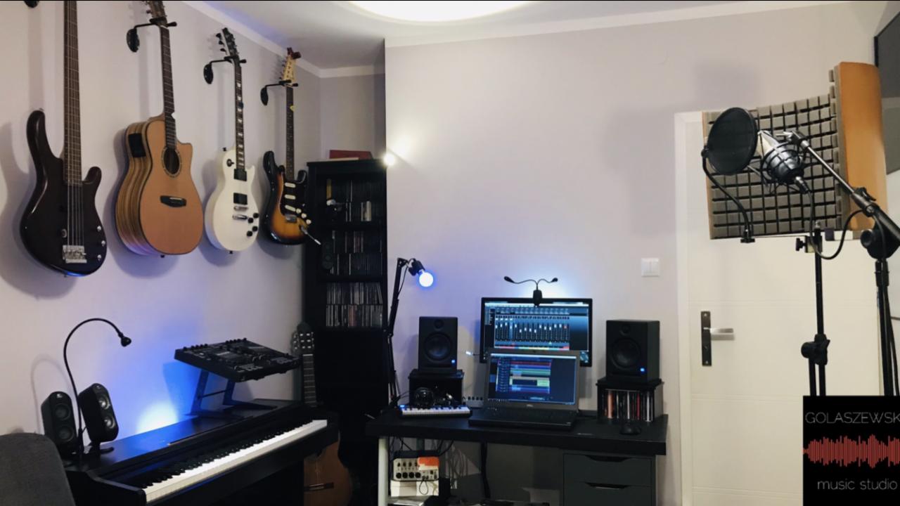 Domowe studio nagrań z pianinem cyfrowym, gitarami na ścianie, mikrofonem studyjnym z ekranem akustycznym oraz komputerem z oprogramowaniem DAW.