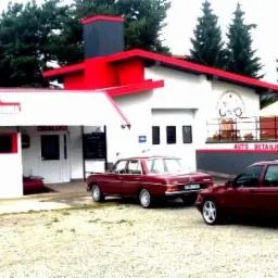 Budynek myjni samochodowej z czerwonymi akcentami, przed którym stoją trzy samochody: Mercedes, Ford Sierra i Mitsubishi Pajero.