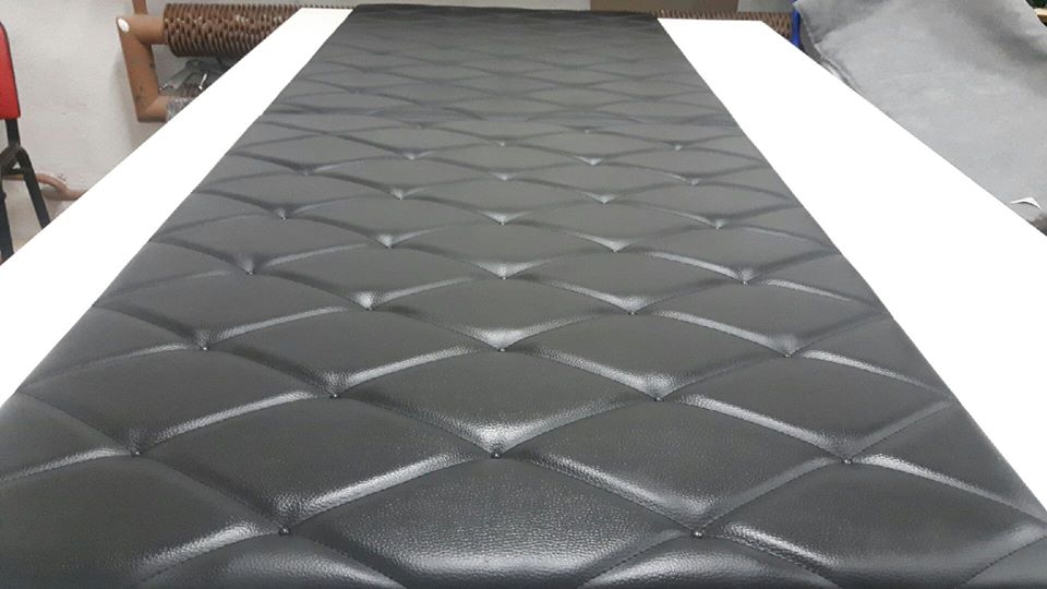 Czarna skóra ekologiczna z pikowaniem w romby, widoczna na stole w warsztacie, z elementami wyposażenia w tle.