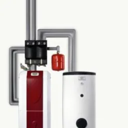 Nowoczesny piec centralnego ogrzewania z czerwonym panelem i biały zasobnik ciepłej wody użytkowej na tle instalacji grzewczej.
