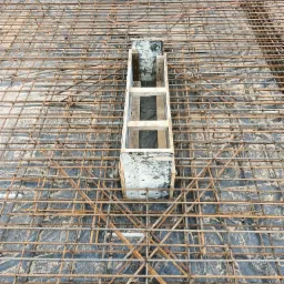 Siatka zbrojeniowa na czarnej folii, z drewnianą formą pośrodku, widok z góry.