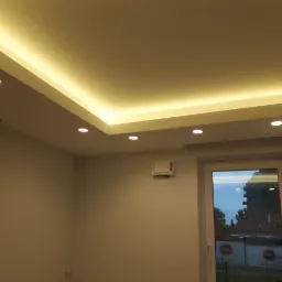 Nowoczesne oświetlenie sufitowe z listwą LED i punktowymi lampami halogenowymi w jasnym pomieszczeniu z widokiem na zewnątrz przez okno.