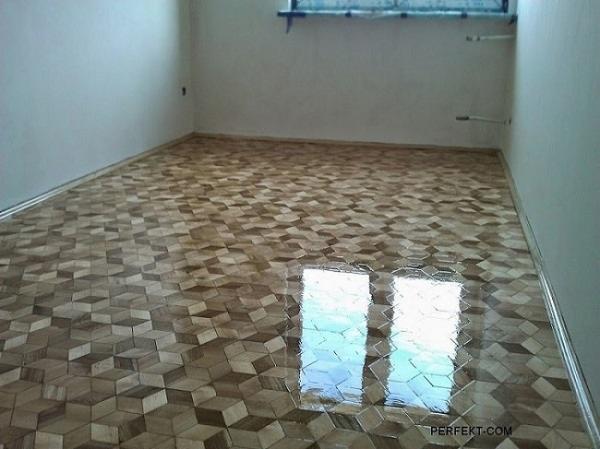 Wycyklinowana podłoga parkietowa z geometrycznym wzorem kostek 3D, lakierowana na wysoki połysk, odbijająca światło okienne w pustym pomieszczeniu.